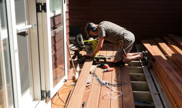Deck Installation by Builders Silverdale – Skilled Deck Builders at Work Builder installing timber deck boards by hand, part of the expert deck builders team at Builders Silverdale