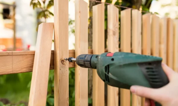 Close-up of Builders Silverdale fencing contractors securing timber panels with a power drill for a new fence.